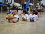 A man carries his child through a flooded area to a safer place after heavy rains caused by Cyclone Remal in Imphal, Manipur, India, May 29, 2024. REUTERS/Stringer