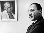 Dr Martin Luther King, Jr stands next to a portrait of Mahatma Gandhi in his office in 1966.