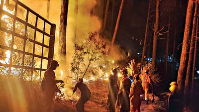 Officials try to douse a fire that erupted in the hills of Varunavat on Wednesday evening. Officials try to douse a fire that erupted in the hills of Varunavat on Wednesday evening.