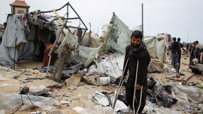 A man looks on as Palestinians inspect a tent camp damaged in an Israeli strike during an Israeli military operation, in Rafah, in the southern Gaza Strip, May 28, 2024. (Reuters)