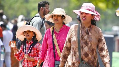 Tourists near India Gate shield themselves from the scorching sun on Thursday afternoon. (Raj K Raj/HT Photo)