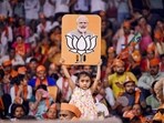 A child holds a placard depicting PM Modi and the BJP election symbol during a public meeting in Uttar Pradesh.(PTI Photo)