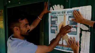 Polling officials put up an election poster outside a polling station in Almi, Himachal Pradesh, (REUTERS) Polling officials put up an election poster outside a polling station in Almi, Himachal Pradesh, (REUTERS)