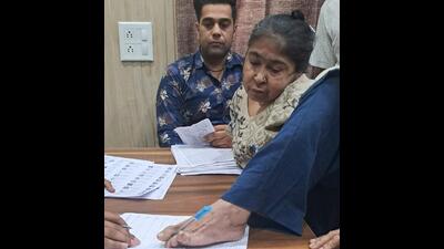 Seema Rani, 47, a differently abled voter from Fazilka, signing the poll register with her foot before voting on Saturday. (HT Photo)