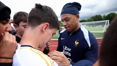France's forward Kylian Mbappe (R) signs an autograph for a fan wearing a Real Madrid jersey (AFP) France's forward Kylian Mbappe (R) signs an autograph for a fan wearing a Real Madrid jersey (AFP)