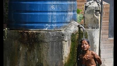 A child bathes from a water tank to beat the heat in Lucknow on Monday. (Deepak Gupta/HT Photo)
