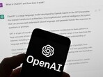 The OpenAI logo is seen on a mobile phone in front of a computer screen which displays output from ChatGPT. The OpenAI logo is seen on a mobile phone in front of a computer screen which displays output from ChatGPT.