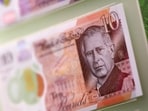 Bank notes and coins that feature an image of Britain's King Charles III are pictured on display.