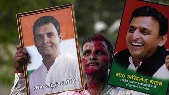 A Samajwadi Party supporter carries portraits of Congress leader Rahul Gandhi and SP chief Akhilesh Yadav. (AP PHOTO)