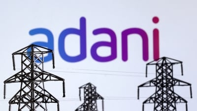 Electric power transmission pylon miniatures and Adani Green Energy logo are seen in this illustration (Reuters)