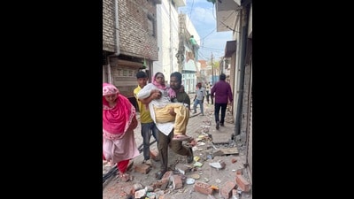 A resident helps his ailing mother move amid a demolition exercise in Akbar Nagar (HT)