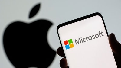 Microsoft logo is seen on the smartphone in front of displayed Apple logo in this illustration taken. (Reuters)