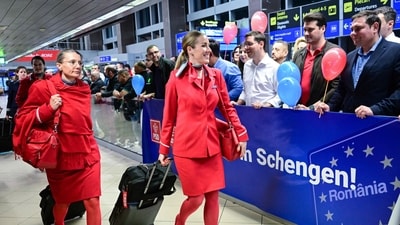 Flight attendants walk next to a banner reading "Welcome to Schengen!" in Romanian a few minutes after midnight, just after Romania's official entry into the European area of free circulation on March 31, 2024. (AFP) Flight attendants walk next to a banner reading "Welcome to Schengen!" in Romanian a few minutes after midnight, just after Romania's official entry into the European area of free circulation on March 31, 2024. (AFP)