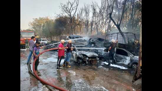Firefighters dousing the flames that engulfed a dozen seized vehicles outside the Zirakpur police station on Tuesday. (HT photo)