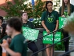 Survivors of the 2012 Sandy Hook Elementary School shooting hold signs during a rally against gun violence on Friday, June 7, 2024 in Newtown, Conn. (AP Photo/Bryan Woolston)