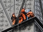 TOPSHOT - Firefighters intercept Polish climber Marcin Banot (2nd-R) as he climbed a building in Puerto Madero wearing an Argentina national football team jersey with Lionel Messi's number 10 in Buenos Aires on June 11, 2024. (Photo by LUIS ROBAYO / AFP)
