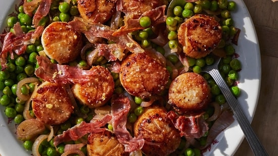 This image released by Weldon Owen shows a recipe for scallops with peas and prosciutto from the cookbook "Out There: A Camper Cookbook: Recipes from the Wild" by Lee Kalpakis. (Brittany Barb/Weldon Owen via AP) This image released by Weldon Owen shows a recipe for scallops with peas and prosciutto from the cookbook "Out There: A Camper Cookbook: Recipes from the Wild" by Lee Kalpakis. (Brittany Barb/Weldon Owen via AP)