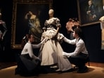 Gallery assistants adjust a gown from Vivienne Westwood's 'Dressed To Scale Collection' A/W 1998/99, estimated to sell for UK£5,000 - UK£8,000, during a preview at Christie's auction house in London. 