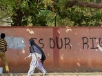 A hijab-wearing student walks past a worker painting a wall to conceal a pro-hijab slogan written on the wall. Representational Photo.. (PTI Photo) 