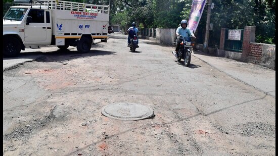 Commuters pass through a broken road in Upkar Nagar in Ludhiana on Saturday. (Manish/HT)