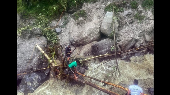 People cross water on a temporary wooden bridge after a landslide following incessant rainfall in Sikkim’s Mangan on Thursday. (ANI)