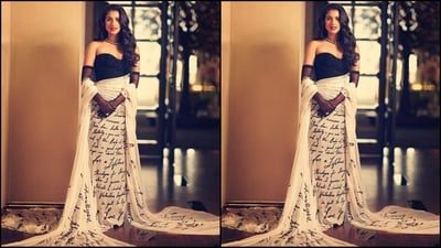 Her outfit showcases an off-shoulder sweetheart neckline, a black crystal-adorned bodice, and a white draped luxurious French chiffon fabric that displays her fiancé's love letter, gifted to her on Merchant's 22nd birthday. The extended hemline and matching stole wrapped around her hands added the perfect touch of drama. (Instagram/@rheakapoor) Her outfit showcases an off-shoulder sweetheart neckline, a black crystal-adorned bodice, and a white draped luxurious French chiffon fabric that displays her fiancé's love letter, gifted to her on Merchant's 22nd birthday. The extended hemline and matching stole wrapped around her hands added the perfect touch of drama. (Instagram/@rheakapoor)