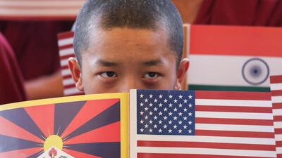 A Tibetan monk holding the US and Tibetan flags while awaiting to welcome the US delegation at the Kangra airport . (REUTERS) A Tibetan monk holding the US and Tibetan flags while awaiting to welcome the US delegation at the Kangra airport . (REUTERS)