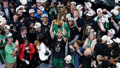 Boston Celtics forward Jayson Tatum (0) celebrates with the trophy on the podium after defeating the Dallas Mavericks in the 2024 NBA Finals (USA TODAY Sports via Reuters Con)
