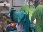 Doctors performing C-section surgery on the woman as she sings a Lord Krishna bhajan. 