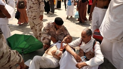 A man effected by the scorching heat is helped by a member of the Saudi security forces as Muslim pilgrims arrive to perform the symbolic 'stoning of the devil' ritual as part of the hajj pilgrimage in Mina, near Saudi Arabia's holy city of Mecca, (Photo by Fadel Senna / AFP) (AFP)