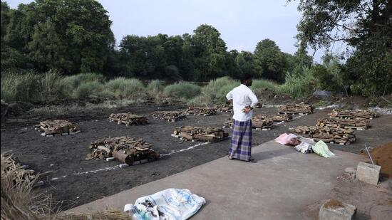 A man stands next to piles of wood arranged for the mass cremation of people, who died after drinking illegally brewed liquor in Kallakurichi district of Tamil Nadu. (AP)