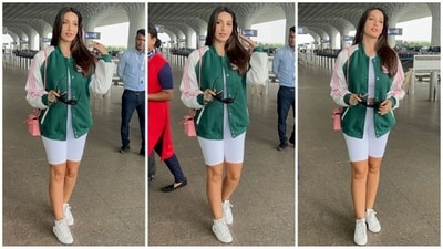 Nora Fatehi never fails to grab the limelight with her undeniable beauty and incredible fashion sense whenever she steps out. Her latest airport look was no exception as she turned heads in a white crop top, matching white cycling shorts, and an oversized dark green varsity jacket. Styled with white sneakers, a pink sling bag, and black sunglasses, she exuded effortless style. (HT photo/VarinderChawla) Nora Fatehi never fails to grab the limelight with her undeniable beauty and incredible fashion sense whenever she steps out. Her latest airport look was no exception as she turned heads in a white crop top, matching white cycling shorts, and an oversized dark green varsity jacket. Styled with white sneakers, a pink sling bag, and black sunglasses, she exuded effortless style. (HT photo/VarinderChawla)