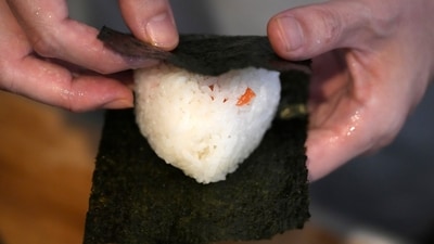 A person wraps seaweed around a rice ball to make onigiri. The humble sticky-rice ball, a mainstay of Japanese food, has entered the global lexicon. (AP) A person wraps seaweed around a rice ball to make onigiri. The humble sticky-rice ball, a mainstay of Japanese food, has entered the global lexicon. (AP)
