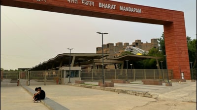 Two people sit outside the Bharat Mandapam’s entry gate. (HT Photo)