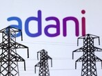 Electric power transmission pylon miniatures and Adani Green Energy logo are seen in this illustration (Dado Ruvic/Reuters)