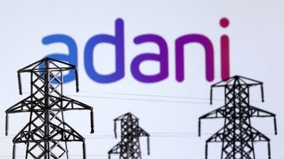 Electric power transmission pylon miniatures and Adani Green Energy logo are seen in this illustration (Dado Ruvic/Reuters)