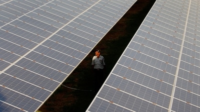 A private security guard walks between rows of photovoltaic solar panels inside a solar power plant at Raisan village near Gandhinagar, Gujarat (Amit Dave/Reuters)