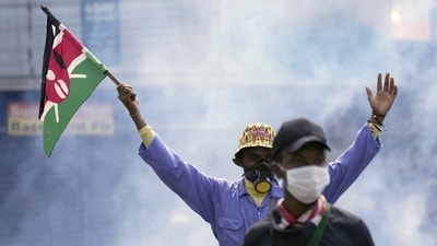 An anti-government protester waves a Kenyan flag as police fire tear gas at them during a protest over proposed tax hikes in a finance bill in downtown Nairobi, Kenya Tuesday, June. 25, 2024. (AP Photo/Brian Inganga)