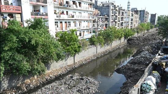 . During a spot check on Thursday, silt and garbage from the nullah had been partly excavated and stashed along the lane, leaving a narrow opening for the sewage water to pass through. However, the situation remained unchanged further down, where the drain was still replete with trash and plastic material. (Arvind Yadav/HT Photo)