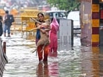 Delhi rain: A woman carries a dog as she wades through a severely waterlogged road following heavy rainfall, in New Delhi on Friday. (ANI Photo/Ishant) Delhi rain: A woman carries a dog as she wades through a severely waterlogged road following heavy rainfall, in New Delhi on Friday. (ANI Photo/Ishant)
