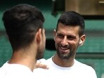 Serbia's Novak Djokovic smiles at Spain's Carlos Alcaraz during a warm up session on centre court at the All England Lawn Tennis Club, in west London on June 27, 2024, the week before the Wimbledon Championships