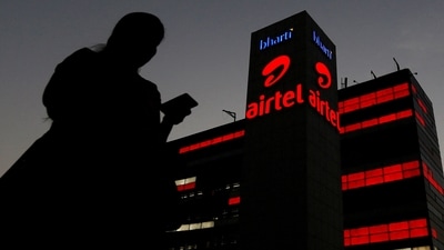 A girl checks her mobile phone as she walks past the Bharti Airtel office building in Gurugram, on the outskirts of New Delhi (Reuters)