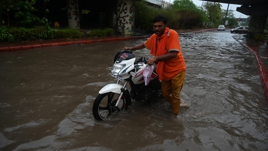 Several commuters were left stranded due to the waterlogging across the Capital. A man can be seen walking through a waterlogged road with his bike.&nbsp;(Sunil Ghosh/Hindustan Times)