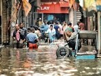 People and vehicles stuck on a waterlogged road near Sarai Kale Khan after heavy rain in Delhi on Friday. (PTI)(HT_PRINT)