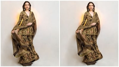 Aditi's glamorous sharara set features a V-neckline and full sleeves, adorned with a vintage floral print on a bronze base. The ensemble is intricately hand-embroidered with badla, sequins, and cut dana, paired beautifully with a tissue organza dupatta, finished with an embroidered printed border. (Instagram/@sanamratansi) Aditi's glamorous sharara set features a V-neckline and full sleeves, adorned with a vintage floral print on a bronze base. The ensemble is intricately hand-embroidered with badla, sequins, and cut dana, paired beautifully with a tissue organza dupatta, finished with an embroidered printed border. (Instagram/@sanamratansi)