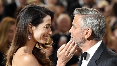 Actor/director George Clooney, right, is greeted by his wife Amal as he arrives in the ballroom at the 46th AFI Life Achievement Award gala honoring him at the Dolby Theatre. (Chris Pizzello/Invision/AP)