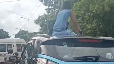 A video shared on social media shows a boy sitting on top of a Tata Nexon car during peak traffic hours in the city. (X) A video shared on social media shows a boy sitting on top of a Tata Nexon car during peak traffic hours in the city. (X)