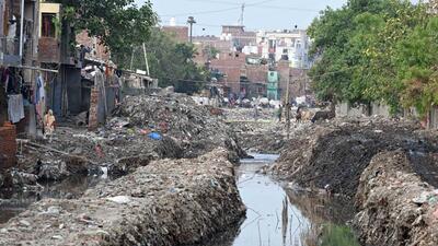 Workers clean the Taimoor Nagar drain, with encroachments on both sides narrowing the width at multiple points. (Sanjeev Verma/HT Photo)
