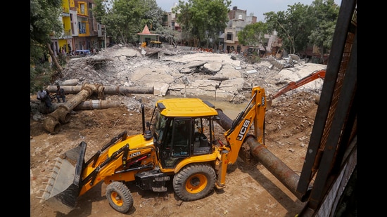 A JCB machine removes the debris after a water tank collapsed due to heavy rainfall, in Mathura on Monday. (ANI)
