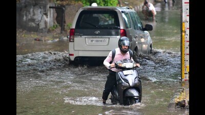 A commuter wades through a waterlogged road in Industrial Area, Chandigarh, following the rain on Tuesday morning. (Keshav Singh/HT)